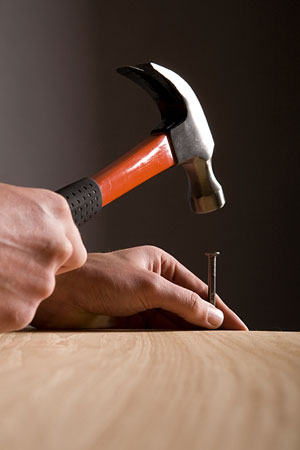 hammer and nail - carpenter hammering a nail into a board